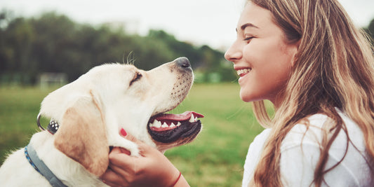 Ein junges Mädchen und ihr Golden Retriever teilen einen liebevollen Moment. Beide strahlen vor Freude, während das Mädchen stolz ihre Rhomberg Ohrhänger mit einem Pfotendesign aus Silber trägt.