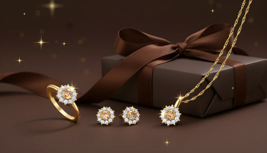 Goldenes Schmuckset mit Diamanten bestehend aus Ring, Ohrsteckern und Halskette, festlich präsentiert vor einem dunkel eingepackten Geschenk mit Schleife.