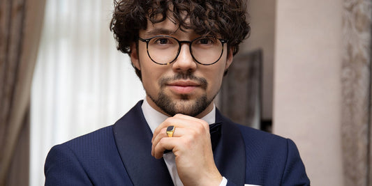 Eleganter Mann mit lockigen Haaren im Anzug mit Siegelring und Brille